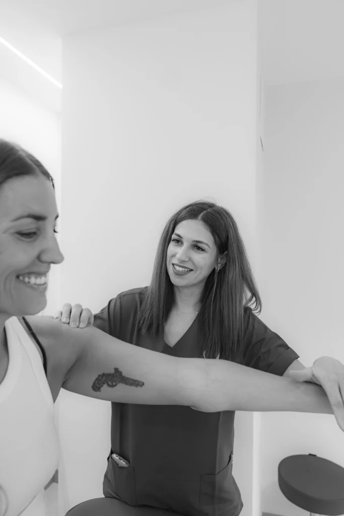 Fisioterapeuta guiando un ejercicio de brazo con una paciente, en blanco y negro
