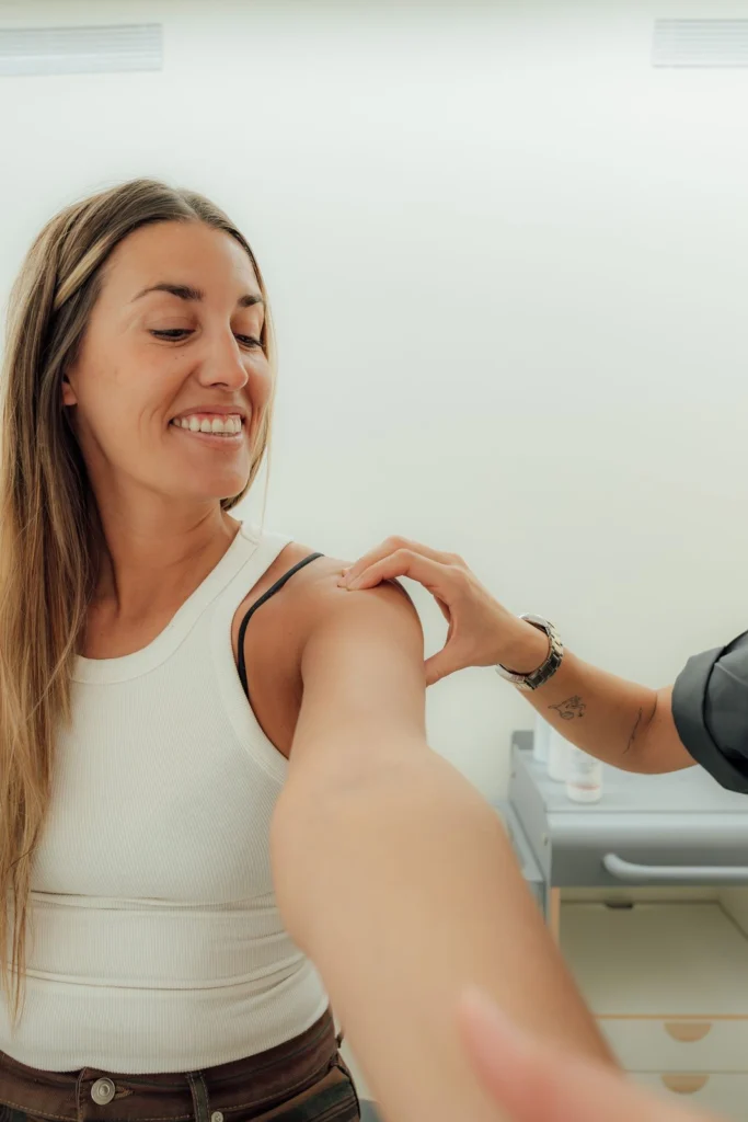Paciente sonriendo durante un ejercicio de hombro guiado por una fisioterapeuta