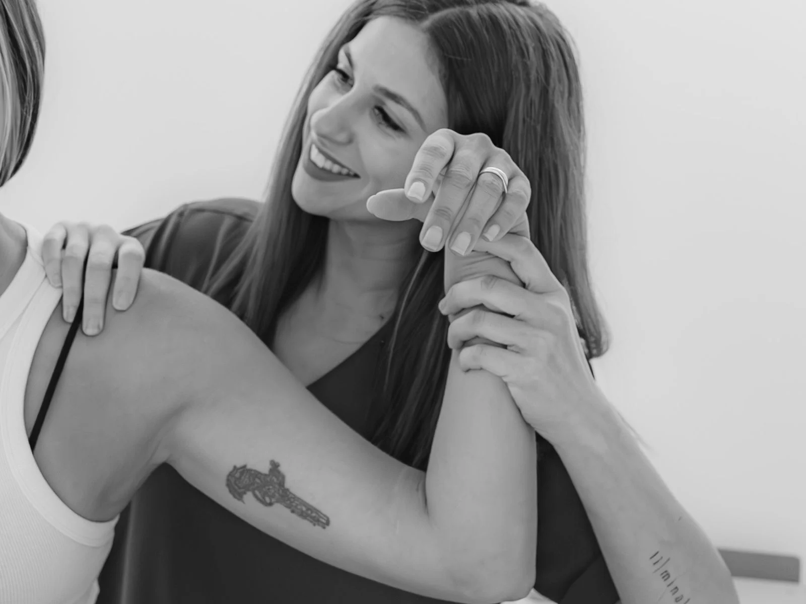 Fisioterapeuta movilizando el hombro de una paciente sonriente, en blanco y negro