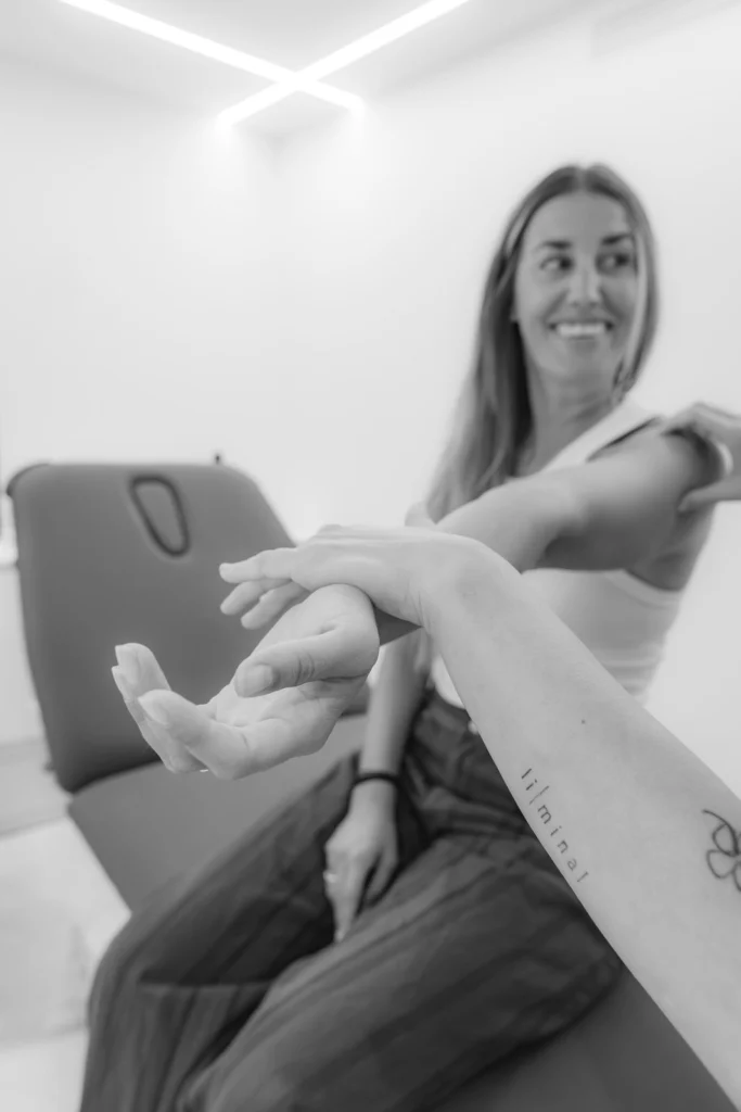 Fisioterapeuta trabajando la movilidad del brazo de una paciente, en blanco y negro