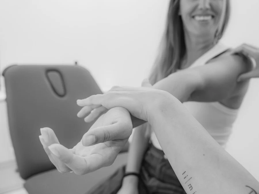 Fisioterapeuta trabajando la movilidad del brazo de una paciente, en blanco y negro