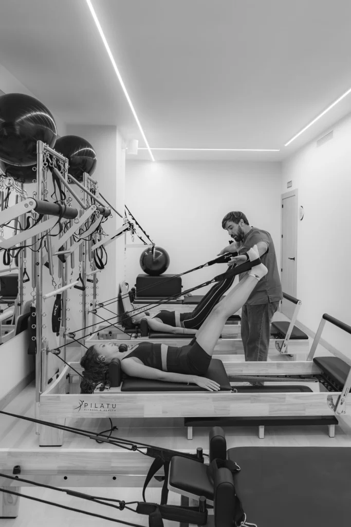 Clase de pilates reformer en grupo reducido, en blanco y negro