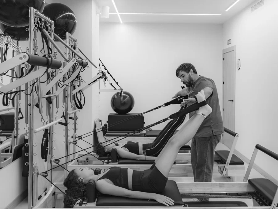 Clase de pilates reformer en grupo reducido, en blanco y negro