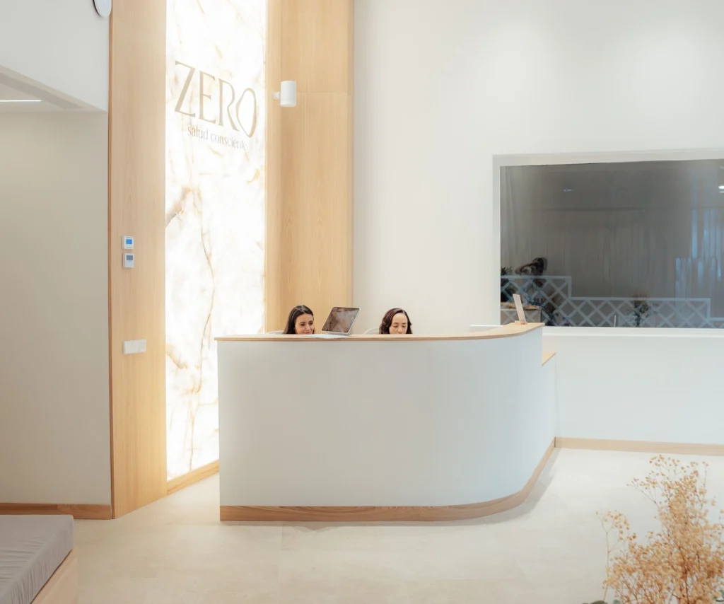 Recepción de Zero Clínica con el logotipo iluminado sobre madera
