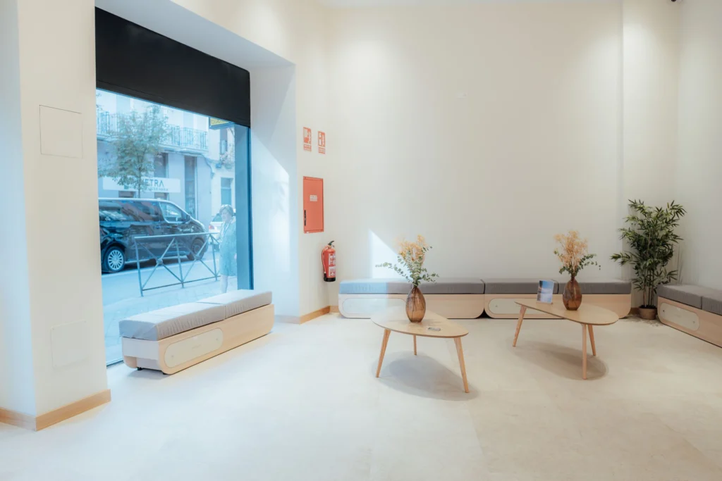 Sala de espera de Zero Clínica con bancos de madera y plantas